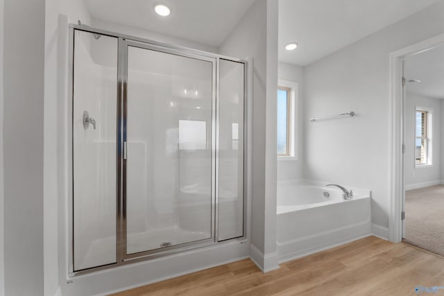 bathroom with independent shower and bath and hardwood / wood-style flooring