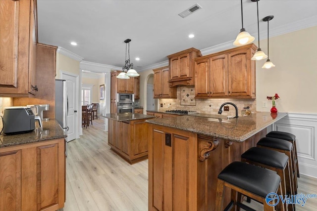 kitchen featuring visible vents, appliances with stainless steel finishes, arched walkways, and brown cabinetry