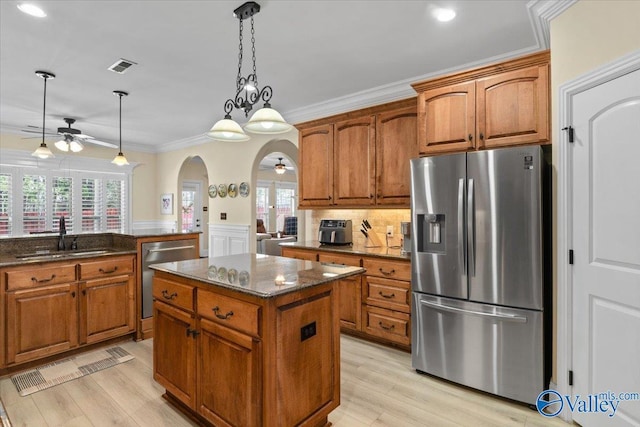 kitchen with arched walkways, stainless steel appliances, a sink, visible vents, and crown molding