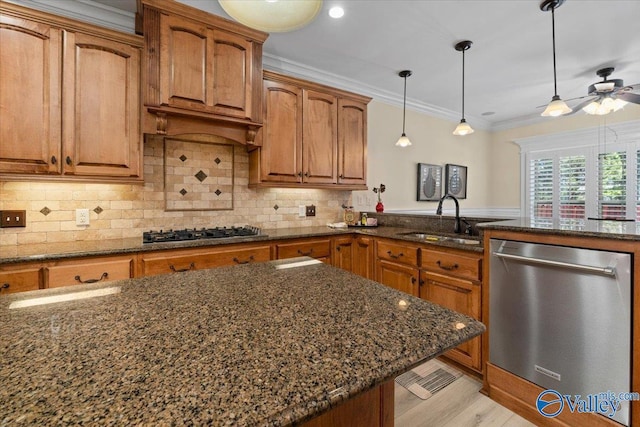 kitchen featuring dishwasher, brown cabinets, dark stone countertops, crown molding, and a sink