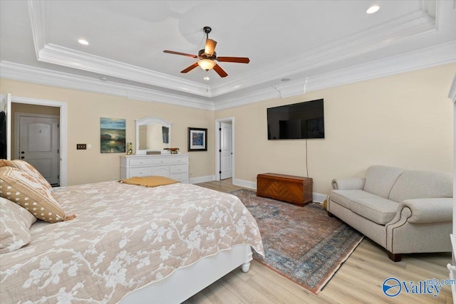 bedroom with a tray ceiling, wood finished floors, and baseboards