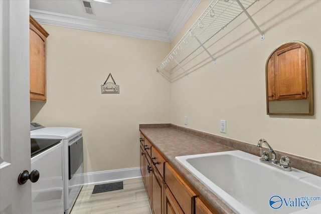 laundry area featuring a sink, visible vents, ornamental molding, cabinet space, and washing machine and clothes dryer