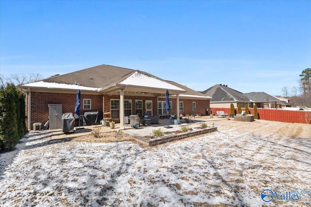 rear view of house with brick siding, a patio area, and fence