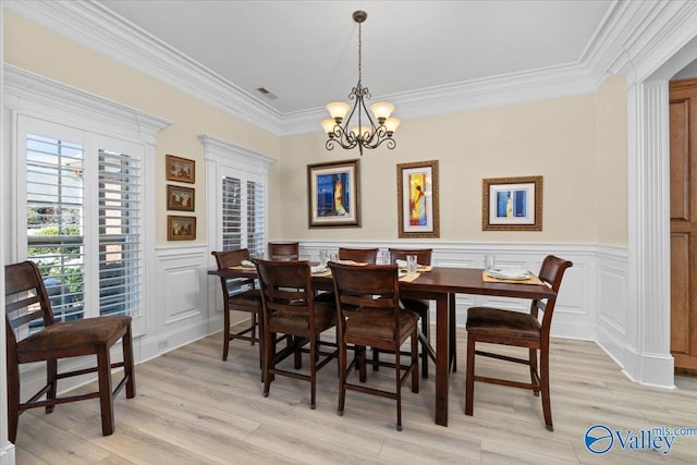 dining room featuring light wood finished floors, visible vents, wainscoting, ornamental molding, and a notable chandelier