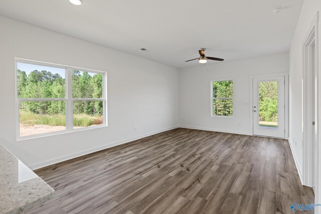 unfurnished room with a healthy amount of sunlight, baseboards, and wood finished floors