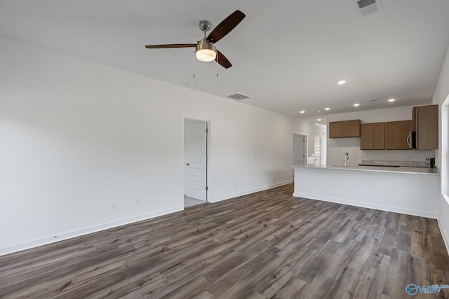 unfurnished living room featuring dark wood-style floors, recessed lighting, visible vents, and a sink