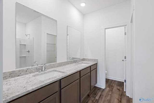 full bath featuring double vanity, toilet, a sink, and wood finished floors