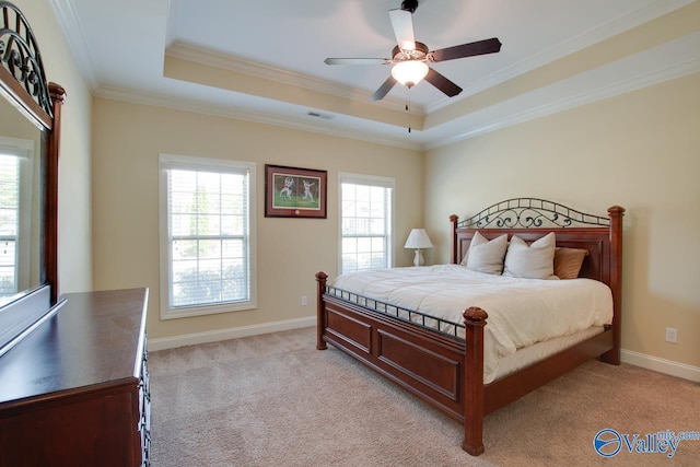 carpeted bedroom with ceiling fan, a tray ceiling, and ornamental molding