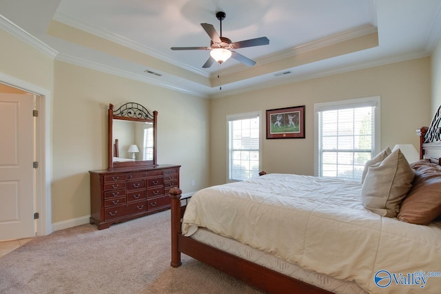 carpeted bedroom featuring a tray ceiling, multiple windows, and ceiling fan