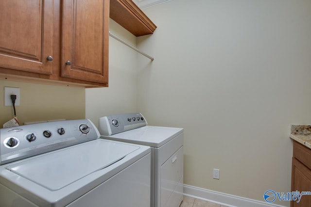 laundry room with washing machine and dryer, cabinets, and light tile patterned floors