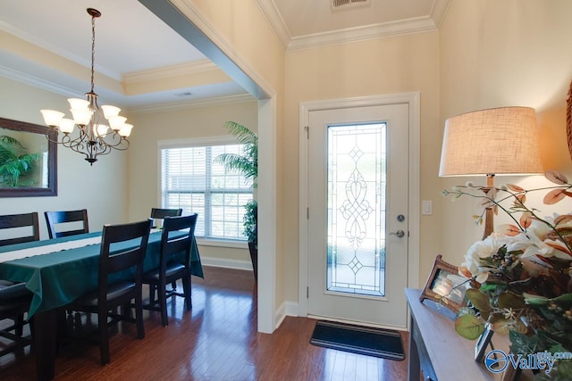 entryway with dark hardwood / wood-style floors, an inviting chandelier, and crown molding