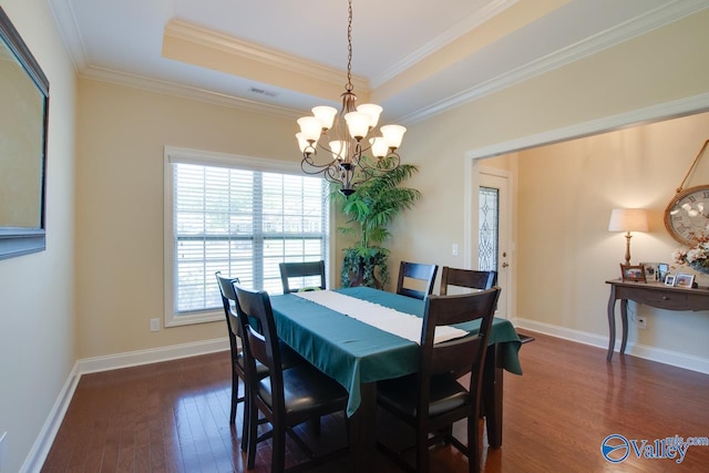 dining space with ornamental molding, a notable chandelier, dark hardwood / wood-style floors, and a raised ceiling