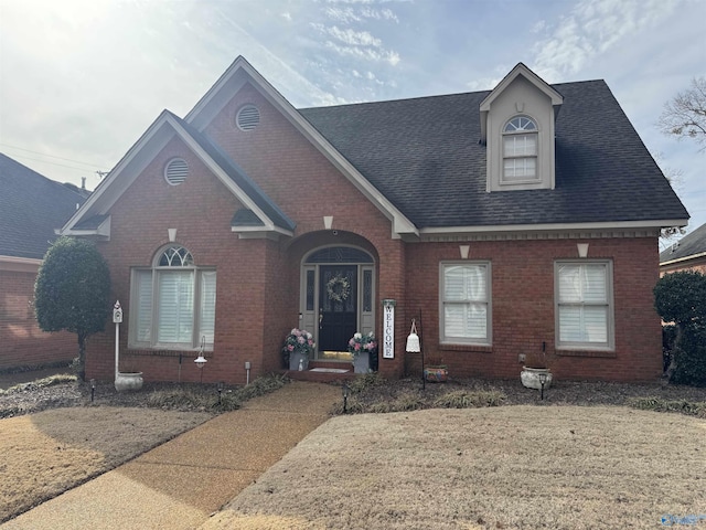 view of front facade with a shingled roof and brick siding