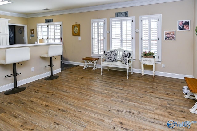 sitting room with visible vents, crown molding, baseboards, and wood finished floors