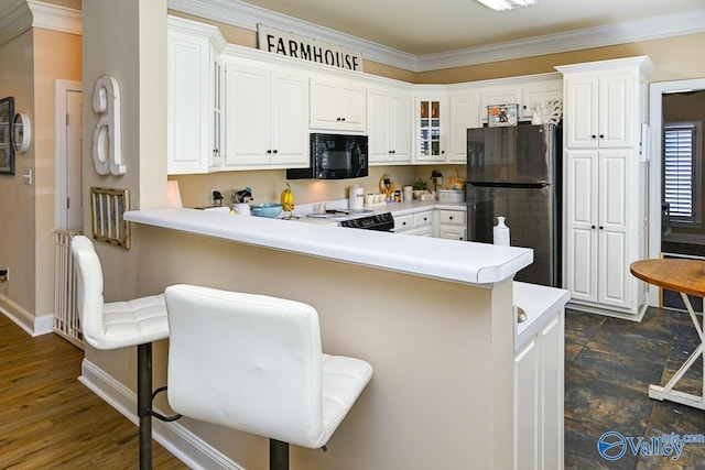 kitchen with black microwave, a peninsula, freestanding refrigerator, electric range oven, and glass insert cabinets