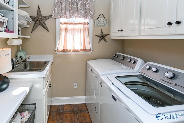 washroom featuring baseboards, cabinet space, a sink, and washing machine and clothes dryer