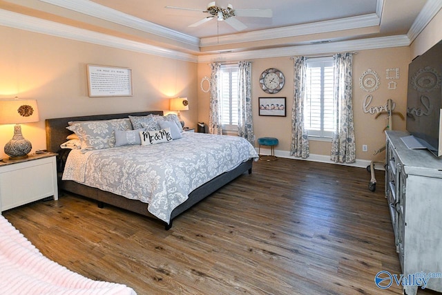 bedroom with ornamental molding, wood finished floors, and a raised ceiling