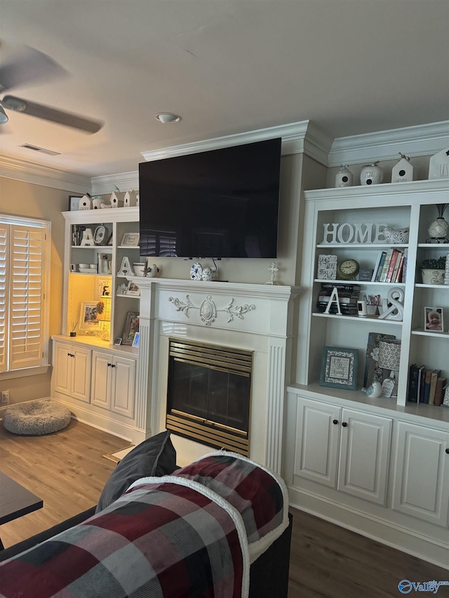 interior space with visible vents, dark wood-type flooring, crown molding, and a glass covered fireplace