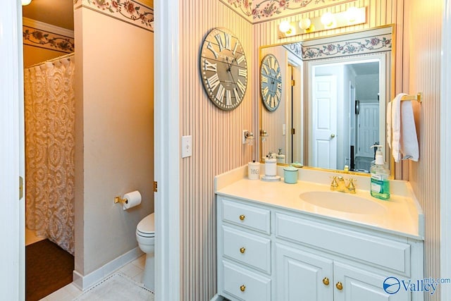 bathroom with toilet, vanity, tile patterned flooring, baseboards, and wallpapered walls