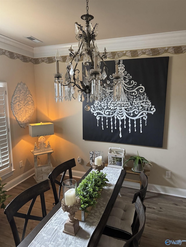 dining room featuring a notable chandelier, wood finished floors, visible vents, baseboards, and ornamental molding