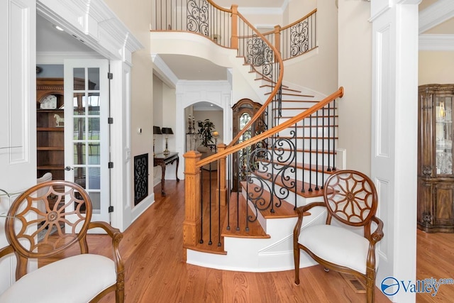 stairway featuring hardwood / wood-style flooring, ornamental molding, and a high ceiling