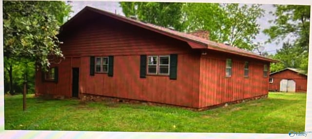 view of side of home featuring an outbuilding and a yard