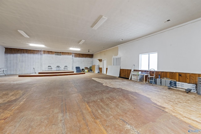 interior space featuring wood walls, ornamental molding, and hardwood / wood-style flooring