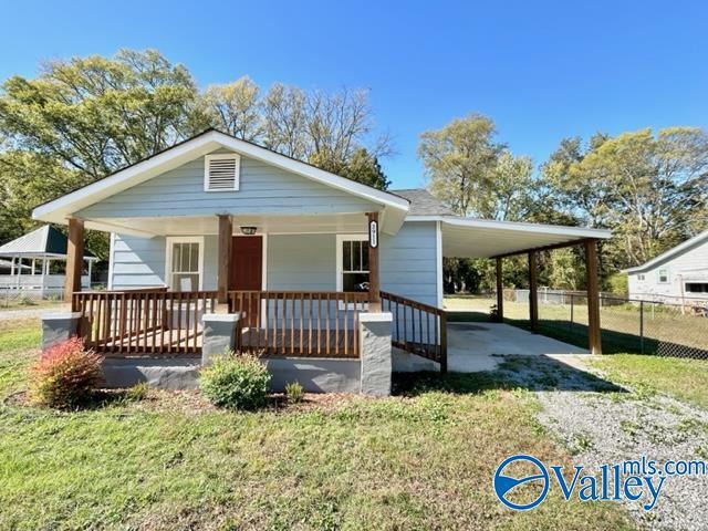 view of front of property with covered porch, a front yard, and an attached carport