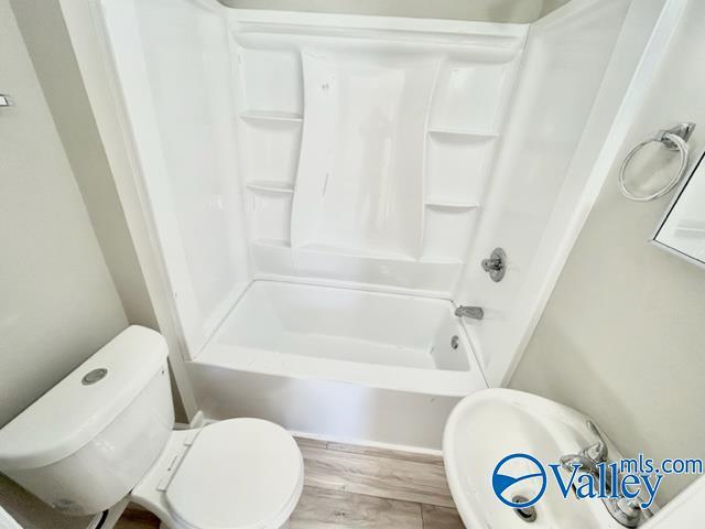 full bath featuring wood finished floors, toilet, and shower / bathtub combination