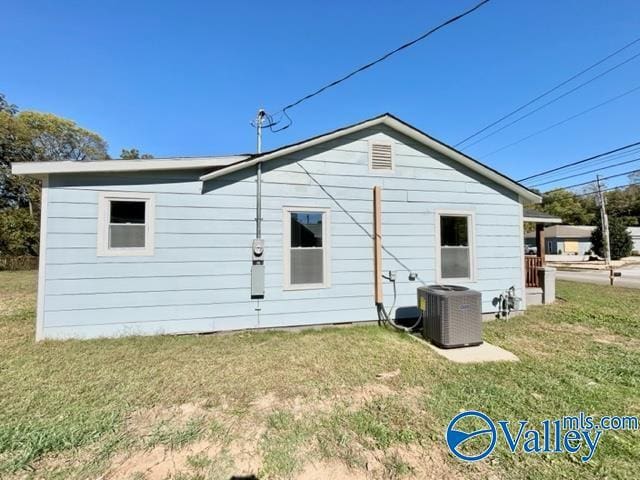 rear view of property with central AC and a lawn