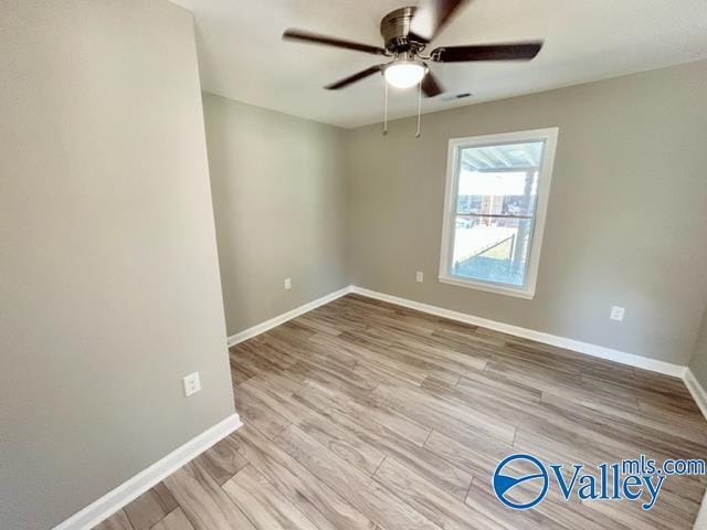 spare room with a ceiling fan, wood finished floors, and baseboards