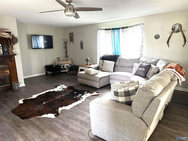 living room featuring ceiling fan, a textured ceiling, and dark wood-type flooring