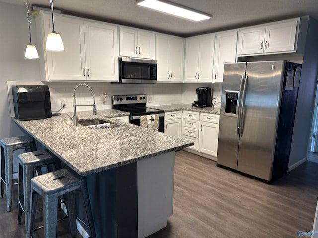 kitchen featuring white cabinets, a breakfast bar, kitchen peninsula, stainless steel appliances, and sink