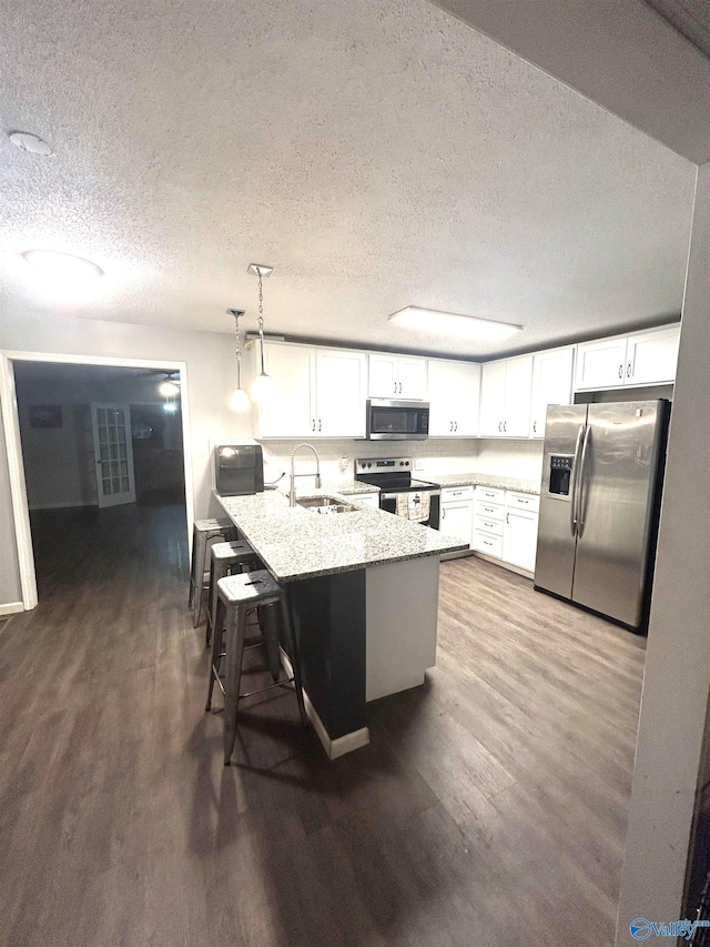 kitchen featuring pendant lighting, a breakfast bar area, appliances with stainless steel finishes, and white cabinetry