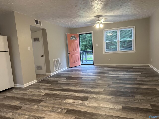 kitchen featuring plenty of natural light, a textured ceiling, white appliances, and dark hardwood / wood-style flooring