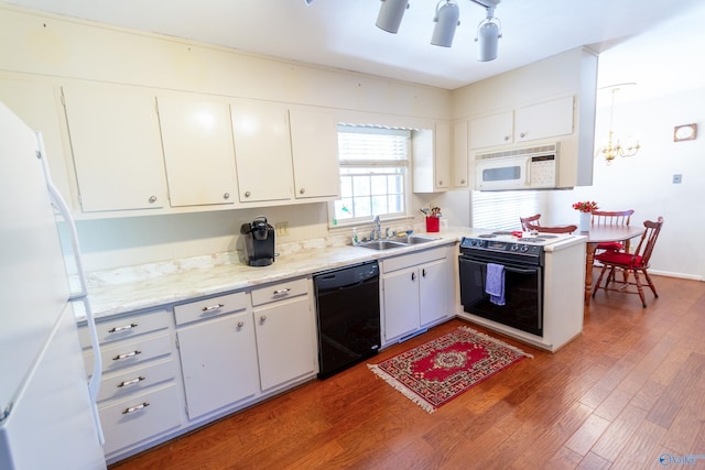 kitchen with white cabinets, wood finished floors, light countertops, black appliances, and a sink