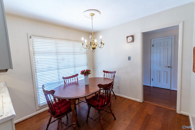 dining space featuring a chandelier, baseboards, and wood finished floors