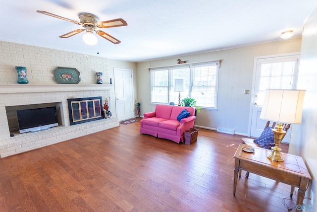 living room featuring a fireplace, wood finished floors, visible vents, and a ceiling fan