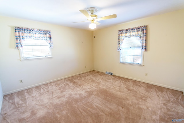 spare room with carpet floors, baseboards, visible vents, and a ceiling fan