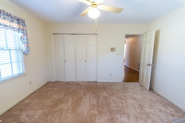 unfurnished bedroom with a closet, light carpet, ceiling fan, and baseboards