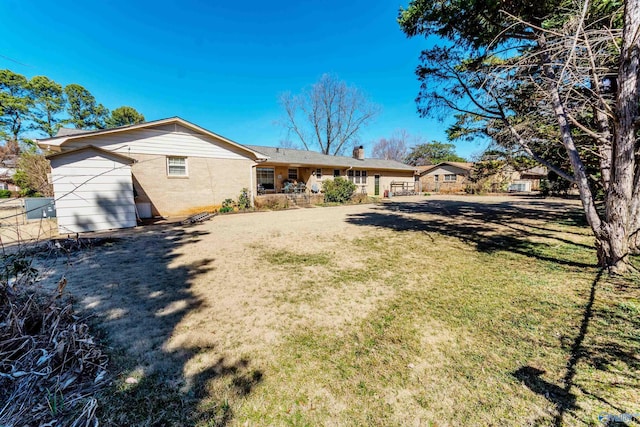 back of house featuring a yard, brick siding, and fence