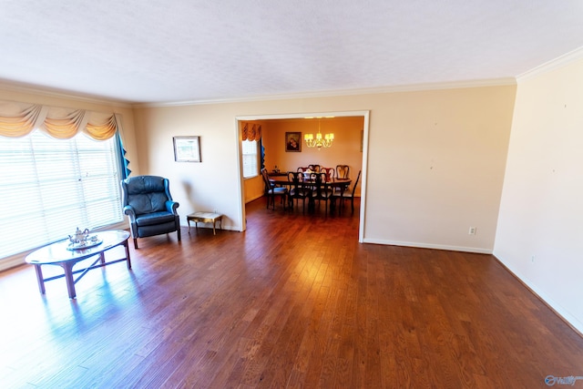 sitting room with a notable chandelier, dark wood-type flooring, baseboards, and crown molding