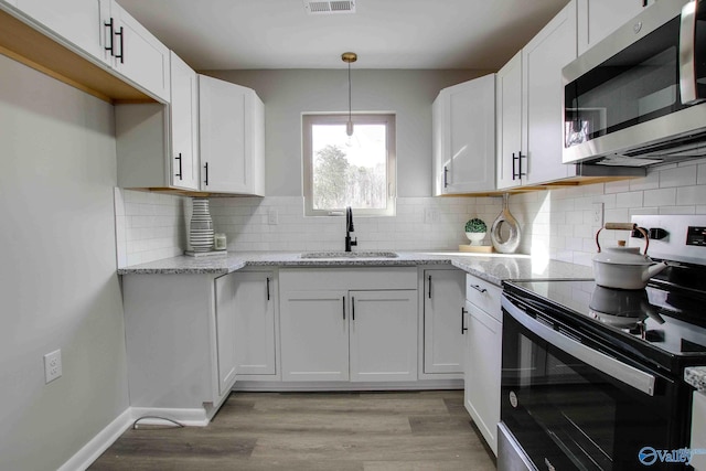 kitchen with white cabinets, stainless steel appliances, light stone counters, and sink