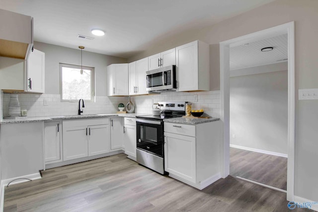 kitchen featuring white cabinetry, sink, stainless steel appliances, pendant lighting, and light wood-type flooring