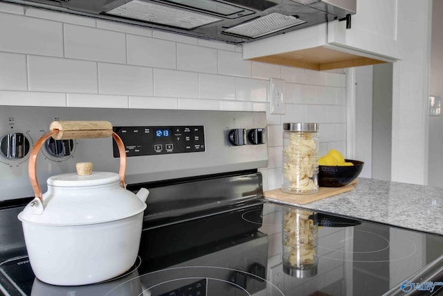 kitchen with stainless steel electric range, light stone countertops, white cabinetry, and tasteful backsplash