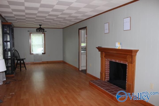 unfurnished living room with hardwood / wood-style flooring, ornamental molding, and a fireplace