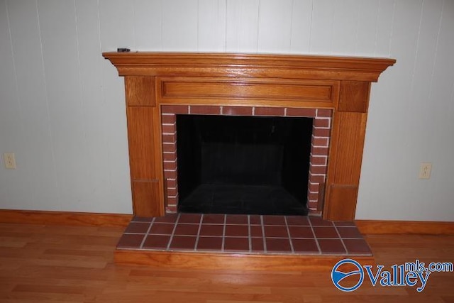 details with a tiled fireplace and hardwood / wood-style floors