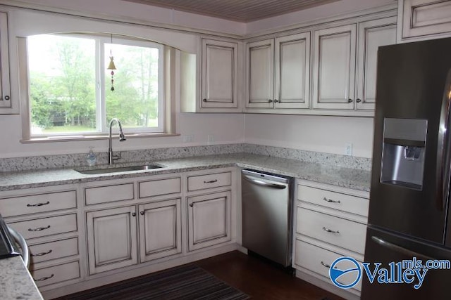 kitchen with light stone countertops, sink, and refrigerator with ice dispenser