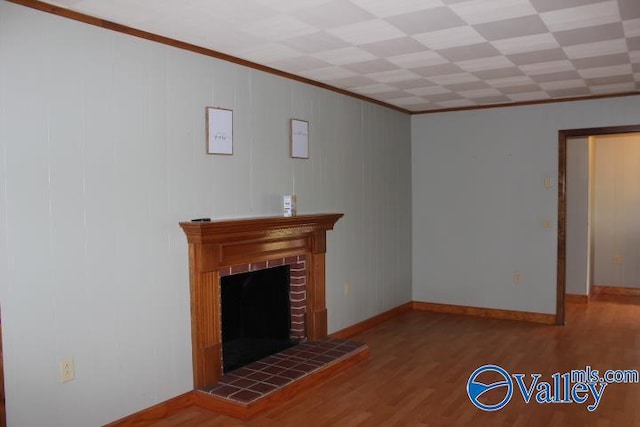 unfurnished living room with hardwood / wood-style flooring, ornamental molding, and a brick fireplace