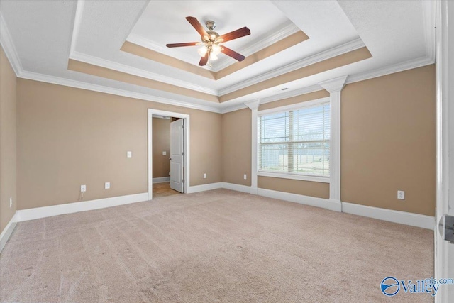 spare room featuring light carpet, ornamental molding, a raised ceiling, and ceiling fan